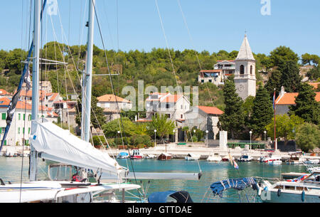 Altes Dorf Prvic Luka auf der Insel Prvic, in der Nähe von Vodice, Kroatien, gesehen von der Seebrücke entfernt, durch die Takelage und Masten eines Segelschiffes Stockfoto