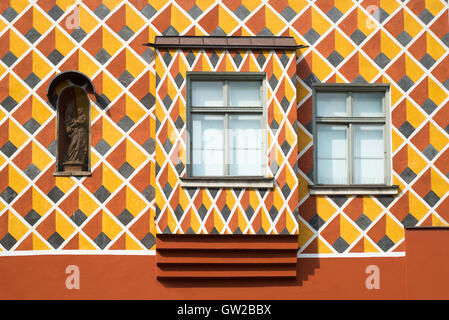 Windows und heilige Figur in einer bunt gemusterten Fassade eines mittelalterlichen Hauses in Wasserburg, Bayern, Deutschland Stockfoto