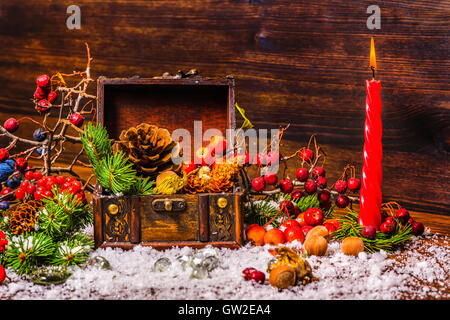 Thanksgiving-Feiertag-Hintergrund mit geöffneten Brust Schatz, Apfel, Nüssen, Zapfen, Beeren, Tanne, Kerze und Schnee, Nahaufnahme Stockfoto