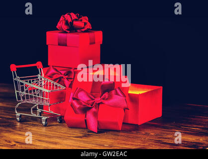 Verkauf-Konzert, Geschenke, Urlaub Grusskarte mit festlichen geöffneten Boxen mit Bogen und shopping Cart auf hölzernen Hintergrund schließen u Stockfoto