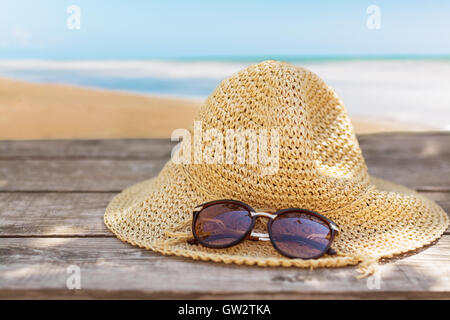 Fedora-Hut und Sonnenbrille auf Holztisch und Meer Landschaft Hintergrund. Stockfoto