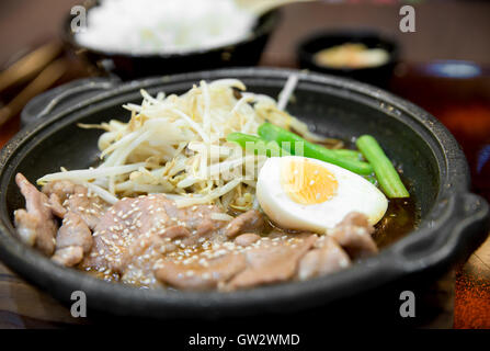 Koreanische würzig gegrilltem Schweinefleisch serviert auf einer heißen Platte mit Beilagen und Reis. Koreanische traditionelle Speisen. Stockfoto