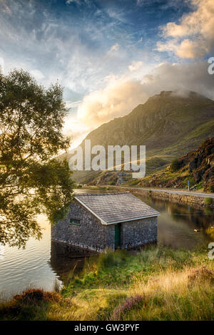 Blick auf Llyn Ogwen See bei Sonnenaufgang mit Blu Sky. Haus im See und Baum. Stockfoto