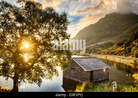 Blick auf Llyn Ogwen See bei Sonnenaufgang mit Blu Sky. Haus im See und Baum. Stockfoto
