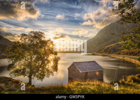 Blick auf Llyn Ogwen See bei Sonnenaufgang mit Blu Sky. Haus im See und Baum. Stockfoto