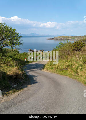 Wicklung einspurigen Straße auf der Insel Colonsay mit Blick über das Meer nach Isle of Mull in der Inneren Hebriden, Schottland, Großbritannien. Stockfoto