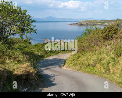 Wicklung einspurigen Straße auf der Insel Colonsay mit Blick über das Meer nach Isle of Mull in der Inneren Hebriden, Schottland, Großbritannien. Stockfoto