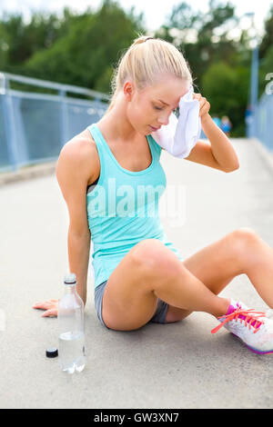 Frau Läufer auf dem Boden saßen und nimmt sich eine Auszeit Stockfoto