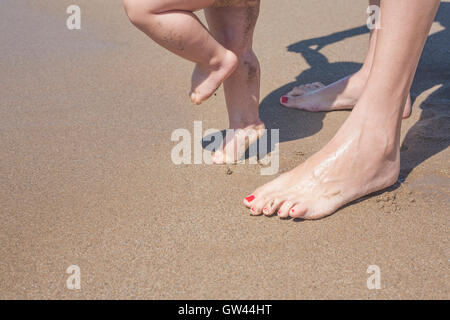 Mutter und Baby Füße am Sandstrand zu Fuß zum ersten Mal Stockfoto