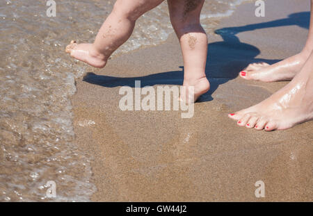 Mutter und Baby Füße am Sandstrand zu Fuß zum ersten Mal Stockfoto