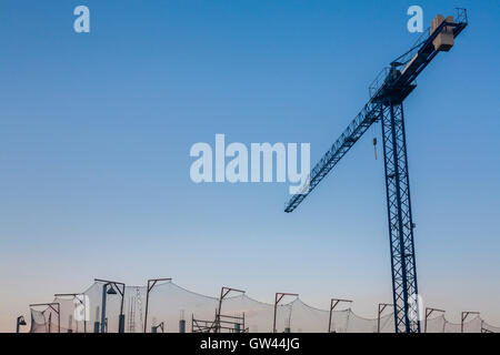 Baustelle mit Kran und Sicherheitsnetz bei Sonnenuntergang über den blauen Himmel Stockfoto