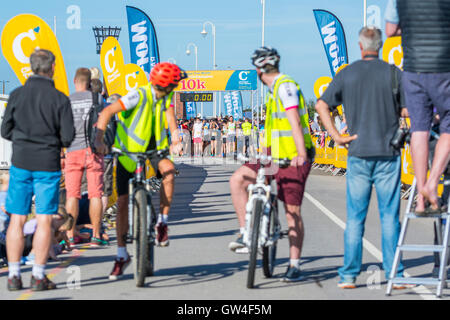 Radfahrer bereit Läufer am Start der Kastanie Haus 10 k Charity Run 2016 in Chichester, West Sussex, England, UK zu führen. Stockfoto