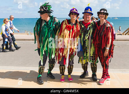 Swanage, Dorset, UK 11. September 2016. Menschenmassen strömen auf den zweiten Tag des Swanage Folk Festival auf einem herrlich warmen sonnigen Tag, Tanzgruppen und Musik entlang der Küste zu sehen. Mitglieder des Orange Peel Morris Tänzer Pose für ein Foto und ein paar Full Moon Morris Tänzer gehen hinter Credit: Carolyn Jenkins/Alamy Live News Stockfoto