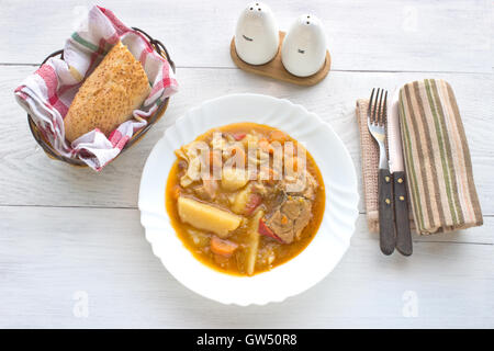 Hühnereintopf mit Kartoffeln in Platte auf weißen Tisch Stockfoto