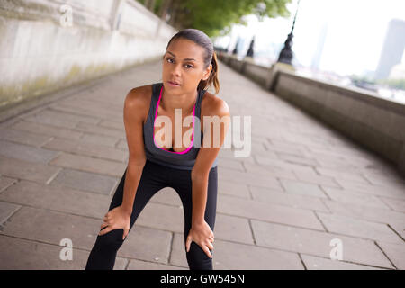 Läufer, beugte sich über ihren Atem zu fangen Stockfoto