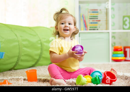 glückliches Kind Mädchen spielen mit Spielzeug drinnen Stockfoto