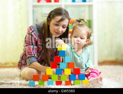 Kleinkind Kind und Mutter bauen Turm spielen Holzspielzeug zu Hause oder Kinderzimmer Stockfoto