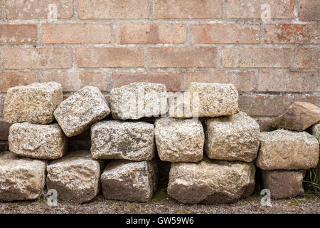Haufen von Granit Blöcke vor roten Backsteinmauer Stockfoto