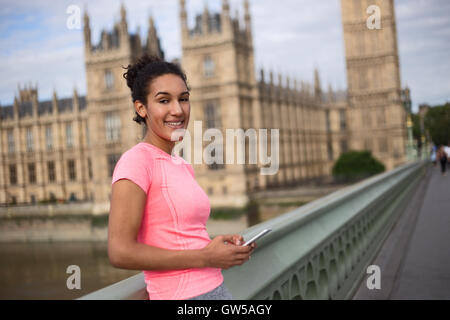 Fitness Mädchen halten ihr Handy in Westminster Brindge, london Stockfoto