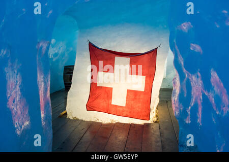 Schweizer Flagge in einem Eis Höhle im Rhonegletscher, beleuchtet von hinten durch das Eis. Stockfoto