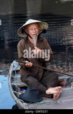 Älterer Mann mit Spitzbart und konische Hut im Boot, Hoi an ein (UNESCO Weltkulturerbe), Vietnam Stockfoto