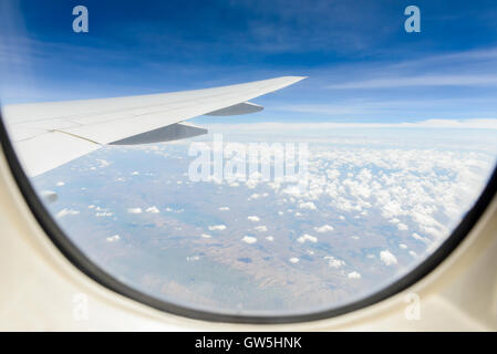 Wolken und Himmel gesehen durch Fenster der Flugzeugkabine zu landen. Stockfoto