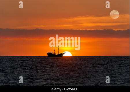 Piraten Schiff Fantasy ist eine alte hölzerne Piratenschiff mit voller Fahnen in einem farbenfrohen Sonnenuntergang Himmel nach Sonnenuntergang am Meer Horizont. Stockfoto