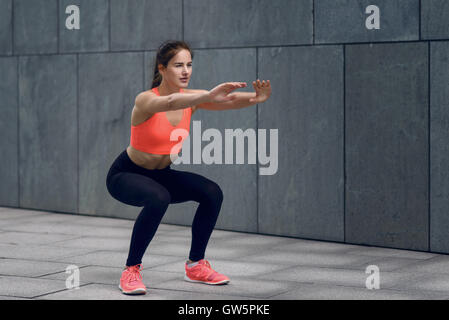 Fit junge Frau macht Kniebeugen, ihren Kern zu verstärken, arbeiten auf einer Matte, Lifestyle und Gesundheit-Konzept Stockfoto