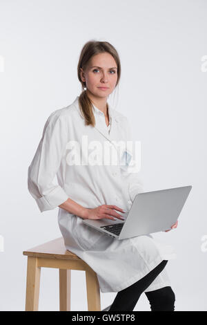 Lächelnd Ärztin arbeitet auf ihrem Laptop vor einem weißen Hintergrund Stockfoto