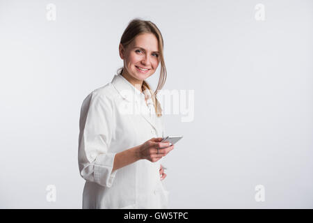 Junge Ärztin, die ihr Smartphone beim Lächeln in die Kamera halten Stockfoto