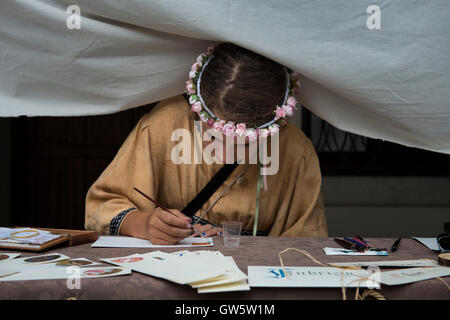 Eine Mädchen auf dem mittelalterlichen fest "Macia" in Spilimbergo veranschaulicht Illuminationen und Manuskripte wie traditionelle Schreiber schreibt. Stockfoto