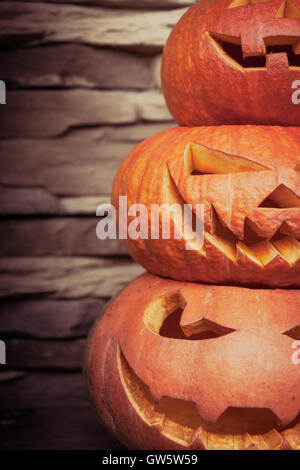 Stapel von Halloween Jack-o-Laternen in vertikaler Ausrichtung auf Stein der Hintergrund jedoch unscharf Stockfoto