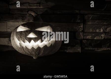 Schwarz / weiß leuchtenden Halloween Jack o ' Lantern in Dunkelheit auf Stein Hintergrund mit Textfreiraum Stockfoto