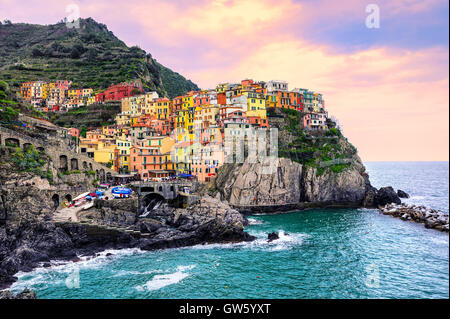 Bunte traditionelle Häuser auf einem Felsen über Mittelmeer am dramatischen Sonnenuntergang, Manarola, Cinque Terre, Italien Stockfoto