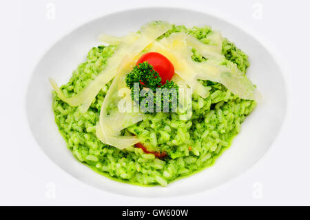 Risotto al Pesto mit Parmesan-Käse-Streifen und Kirschtomaten, serviert in einem weißen Teller Stockfoto