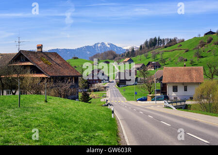 Traditionelle hölzerne Häuser in einem kleinen Schweizer Dorf mit Schnee Gipfel der Alpen im Hintergrund, Zentralschweiz Stockfoto