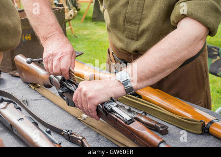 Ein 40er Jahre Heritage Day mit Detail eines alten Soldaten zeigen, wie man eine Gewehr, Armee-jüngstere Söhne laden Stockfoto