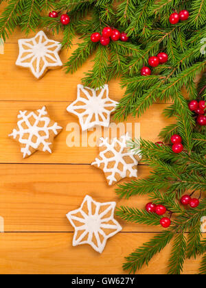 Weihnachtsbaum und rote Beeren und Sterne Cookies auf den Holzplanken-Hintergrund Stockfoto