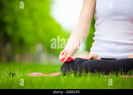 Junge schöne Frau, die beim Yoga im Park. Stockfoto