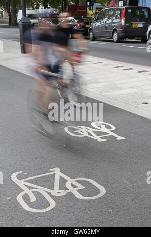 Zwei Radfahrer (verschwommen wegen Geschwindigkeit) auf Londons Zyklus neue Ost-West-Autobahn am Victoria Embankment in Westminster Stockfoto