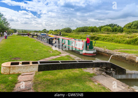 Bunte Lastkähne auf der Durchreise eine der 16 sperrt Caen Hill auf die Kennet & Avon Kanal nr Devizes, Wiltshire, England, UK Stockfoto