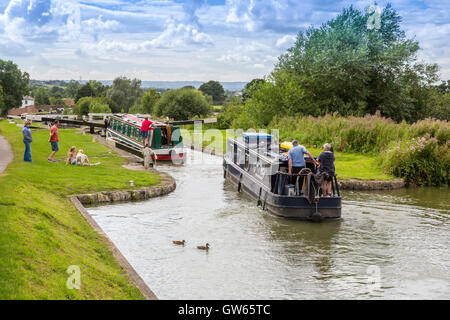 Bunte Lastkähne auf der Durchreise eine der 16 sperrt Caen Hill auf die Kennet & Avon Kanal nr Devizes, Wiltshire, England, UK Stockfoto