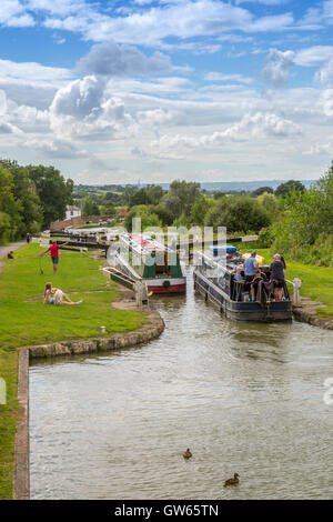 Bunte Lastkähne auf der Durchreise eine der 16 sperrt Caen Hill auf die Kennet & Avon Kanal nr Devizes, Wiltshire, England, UK Stockfoto