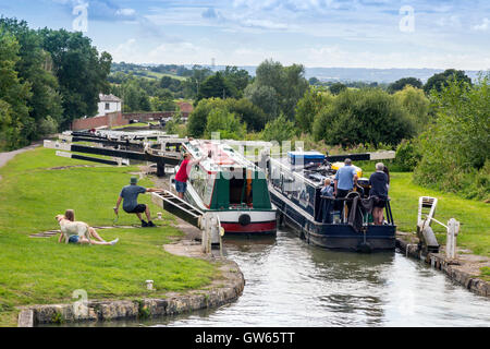 Bunte Lastkähne auf der Durchreise eine der 16 sperrt Caen Hill auf die Kennet & Avon Kanal nr Devizes, Wiltshire, England, UK Stockfoto