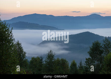 Atemberaubende Landschaft, der idyllische Landschaft mit sanften Hügeln, die im Morgennebel verschleiert. Luftaufnahme von einem Hügel Bauernhaus auf einem nebligen s Stockfoto