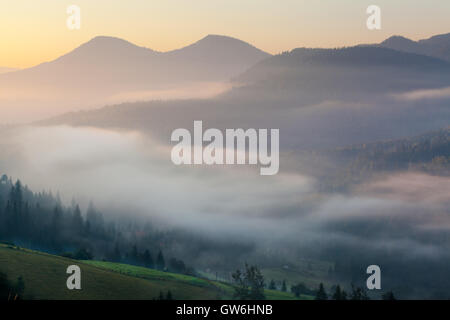 Atemberaubende Landschaft, der idyllische Landschaft mit sanften Hügeln, die im Morgennebel verschleiert. Luftaufnahme von einem Hügel Bauernhaus auf einem nebligen s Stockfoto