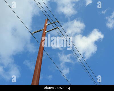 Ein Telefonmast ähnelt das Kreuz steht vor einem blauen Himmel Wolke gefüllt. Stockfoto