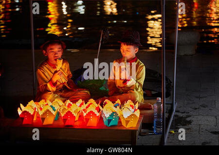 Junge Burschen Verkauf schwimmende Kerzen, Laternen und Essen Mais, Hoi an ein (UNESCO Weltkulturerbe), Vietnam Stockfoto
