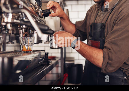 Beschnitten, Schuss von Barista bereiten Sie eine Tasse Kaffee mit einer Kaffeemaschine ausgestattet. Cafe Arbeiter einen Kaffee. Stockfoto