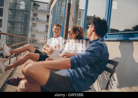 Drei jungen Freunde im Café im Freien. Gemischtrassigen Gruppe von jungen Leuten am Café-Tisch im Freien entspannen. Stockfoto